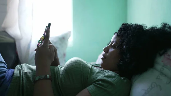여성은 침대에 누워서 전화를 있었습니다 아프리카 미국인 스마트폰을 있습니다 — 스톡 사진