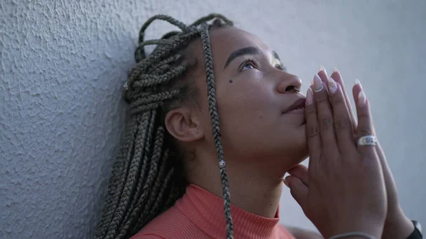 One spiritual young black woman praying to God pleading help and support. A faithful Brazilian adult girl in prayer looking up at sky with HOPE and FAITH