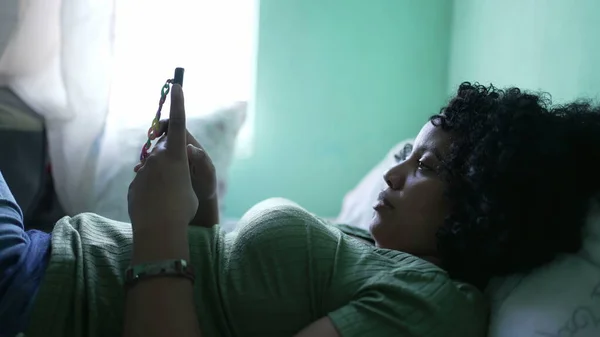 여성은 침대에 누워서 전화를 있었습니다 아프리카 미국인 스마트폰을 있습니다 — 스톡 사진