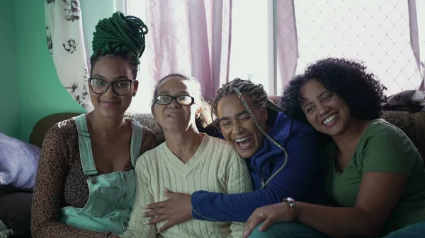 Happy Brazilian people hanging out together at home living room couch. Group of South American daughters united around senior mother. Authentic family love