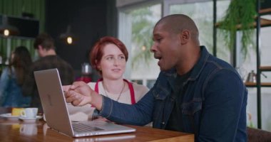 Siyahi bir girişimci, genç bayan çalışana bilgisayarla çevrimiçi sipariş teslimatı hakkında konuşmalarını açıklıyor. Bilgisayarın önünde iş hakkında konuşan iki farklı insan.