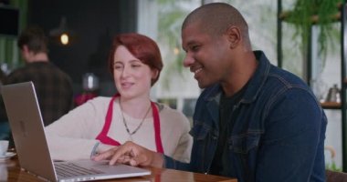 Dizüstü bilgisayarın önünde iki erkek ve kadın çalışan küçük işletme restoranında oturmuş internetten siparişleri kontrol ediyorlar.