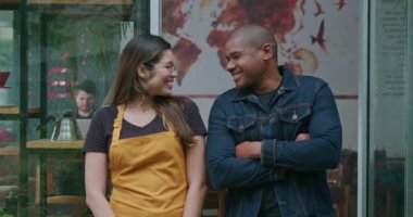 Kafe portresinin iki farklı İspanyol çalışanı gülümsüyor. Güney Amerikalı bir kadın çalışanı olan siyah bir müdür restoran girişinin önünde duruyor.