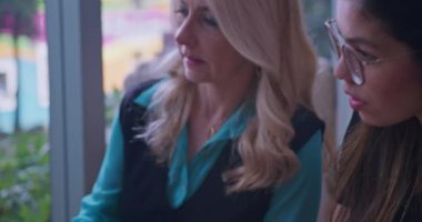 Müdür, yeni bayan çalışana iş açıkladı. Laptopçu dükkanında oturuyor. Bilgisayar kullanarak birlikte çalışan iki farklı personel.. 