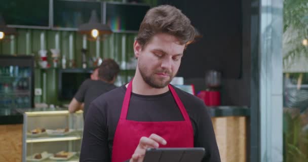 一位快乐的男性员工站在小商业咖啡店前笑着 在咖啡店工作的年轻男子 巴里斯塔 相貌像 — 图库视频影像