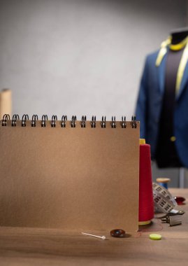 Ahşap masada defter ve dikiş aletleri. Giysi mağazası iş yeri kavramı