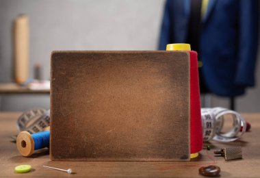 Tahta isim levhası ve ahşap masada dikiş aletleri. Giysi mağazası iş yeri kavramı