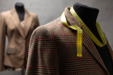 Terzi mankeni ve mezura üzerindeki takım elbise ceketi. Giysi mağazası iş yeri kavramı