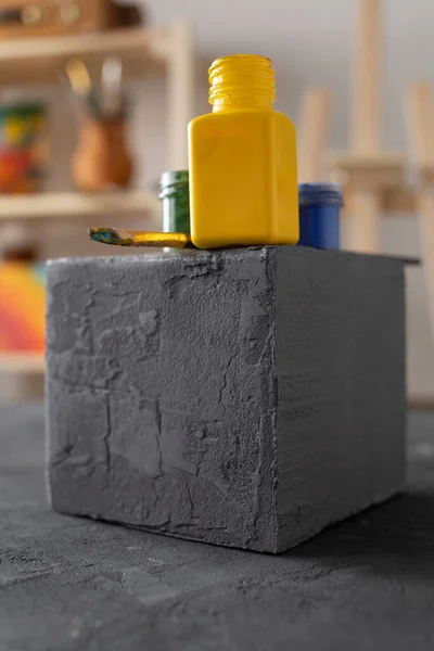 Ressam stüdyosunda boyacı aletleri. Ahşap masada boya fırçası ve şişe. Masa arkası dokusunda boya fırçası ve sanat malzemeleri.