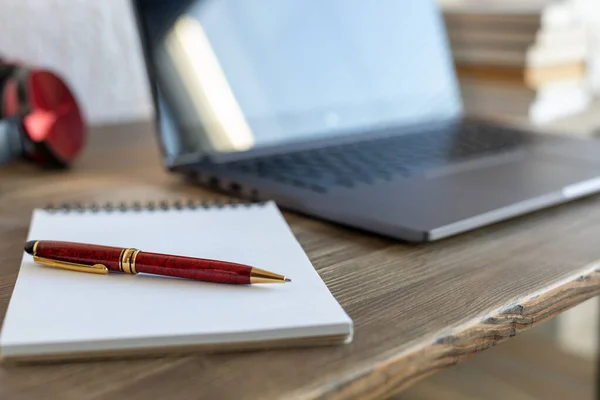 Ofisteki masada dizüstü bilgisayar ve defter var. Çevrimiçi öğrenim için çalışma yeri