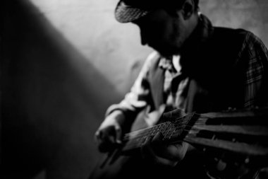 Adam akustik gitar çalıyor. Duvara yakın klasik akustik gitarıyla stüdyoda müzisyen.