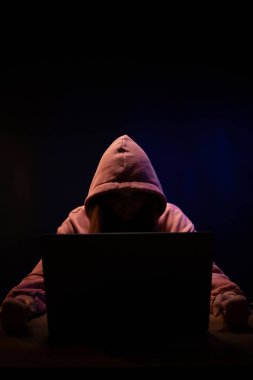 Bilgisayar laptopunun önünde bir hacker var. Karanlık oda geçmişindeki kadın hacker.