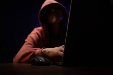 Bilgisayar laptopunun önünde bir hacker var. Karanlık oda geçmişindeki kadın hacker.