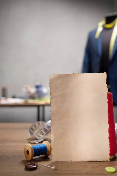 Ahşap masada eski kağıt ve dikiş aletleri. Giysi mağazası iş yeri kavramı