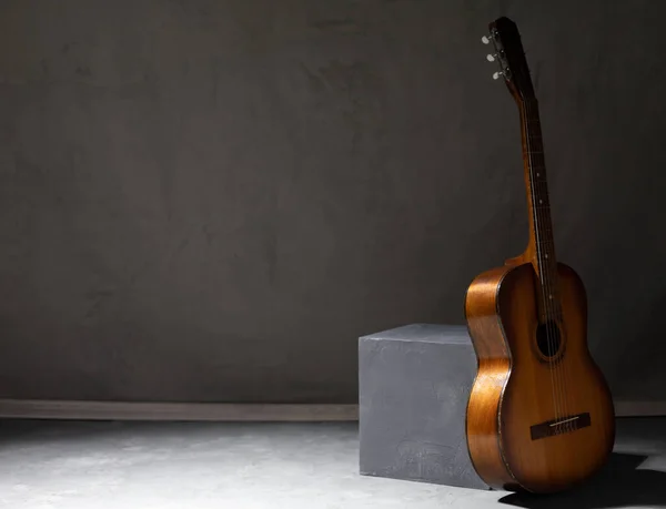 Yerde akustik gitar var. Stüdyoda müzik konsepti, duvarın yanında klasik gitar.