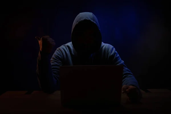 Bilgisayar laptopunun önünde bir hacker var. Karanlık oda arka planında bir hacker.