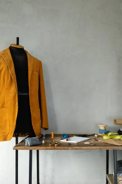 Sewing tools and tailor suit jacket on tailor mannequin. Concept of clothes atelier workplace