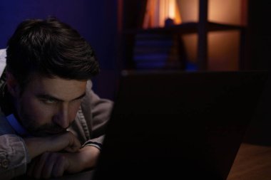 Dizüstü bilgisayarın çalıştığı yere bakan bir adam. İş adamı evde çalışıyor.