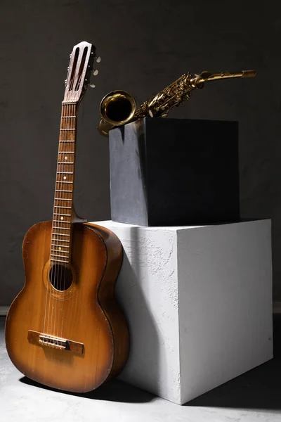 Yerde akustik gitar ve saksafon var. Stüdyoda müzik konsepti ve duvarın yanında müzik aleti