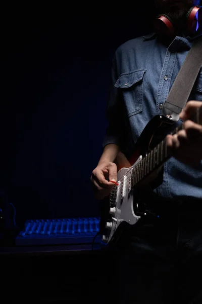 Man playing electric guitar. Musician in record studio holding electric guitar