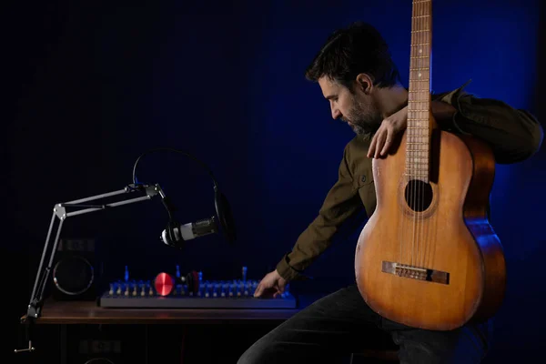Oturan ve gitar çalan adam. Müzik stüdyosunda akustik gitar çalan müzisyen.