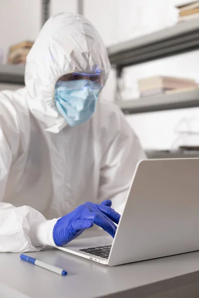 Scientist working computer laptop looking at test tube with liquid reagent. Lab scientist and chemical laboratory   glassware