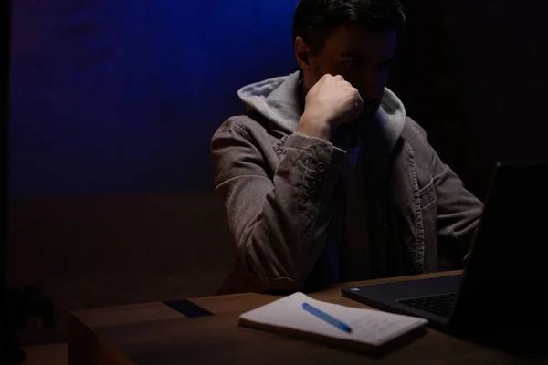 Dizüstü bilgisayarın çalışma yerinde düşünen bir adam. İş adamı evde çalışıyor.