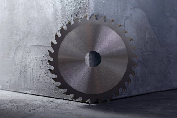 Circular saw blade near concrete cube at abstract cement background texture. Construction idea concept