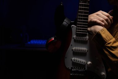 Elektro gitar çalan adam. Müzik stüdyosundaki müzisyen elektro gitar tutuyor.