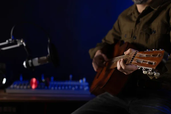 Adam şarkı söylüyor ve gitar çalıyor. Müzik stüdyosunda akustik gitar çalan müzisyen.