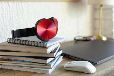 Stack of books and headphones at table in office. Workplace for online study