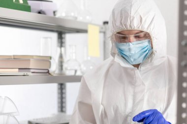 Bilgisayar tableti üzerinde çalışan bilim adamı sıvı reaksiyonla test tüpüne bakıyor. Laboratuvar bilimcisi ve kimya laboratuarı cam eşyalar.