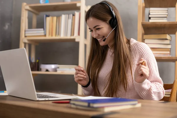 Girl speaking in headphones and writing at notebook. Student woman online larning. Creative inspiration study concept