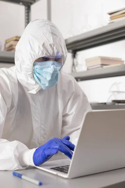 Scientist working computer laptop looking at test tube with liquid reagent. Lab scientist and chemical laboratory   glassware