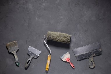 Paint roller and putty knife at cement floor. Tool construction concept on concrete background