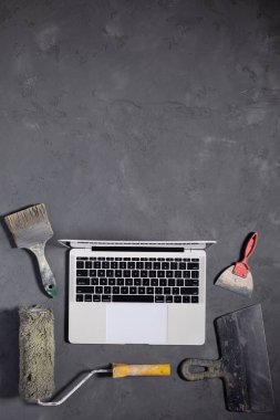 Computer laptop at cement floor. Laptop and construction tool on concrete background