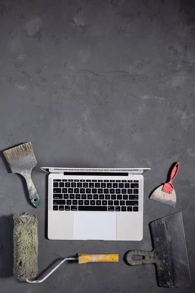 Computer laptop at cement floor. Laptop and construction tool on concrete background