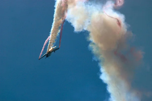 澄んだ青空に対して煙の後に急なダイビングで倒立したアクロバティックな航空機 — ストック写真