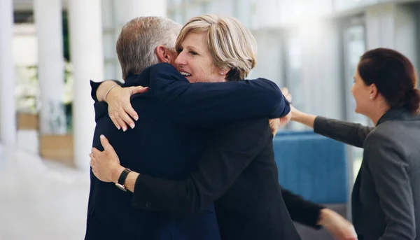 Cropped shot of two mature businesspeople hugging each other while in the office during the day — Zdjęcie stockowe