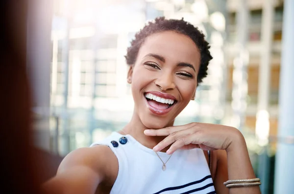 All she needs is her smile to glow up her selfies. Cropped portrait of an attractive young businesswoman taking a selfie in a modern workplace. — Stock Fotó