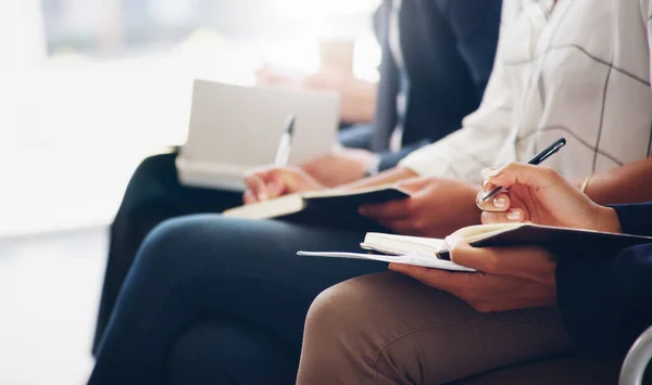 Cropped shot of unrecognizable businesspeople sitting and writing notes in a book while in the office during the day Fotos De Stock