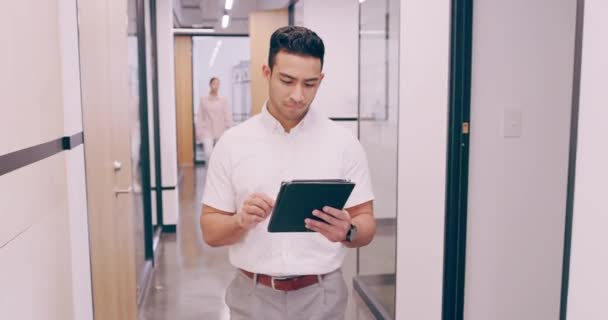 4k video footage of a young businessman working on a tablet as he walks through his office — Stockvideo