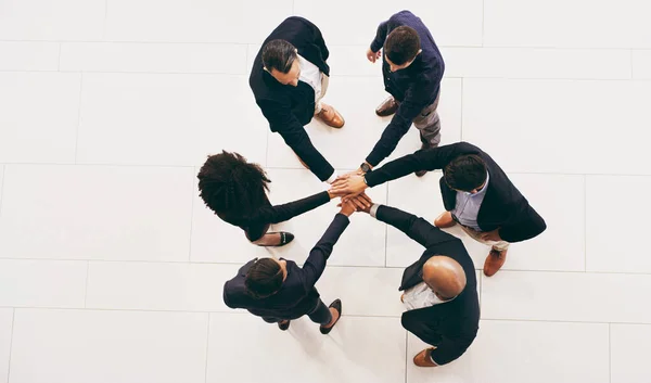 Teamwork turns the wheels of a business. High angle shot of a group of businesspeople joining their hands in solidarity. — Stok fotoğraf