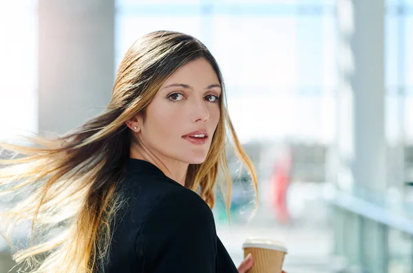 Confidence is key. Cropped portrait of an attractive young businesswoman holding a cup of coffee while walking through a modern office. — стоковое фото