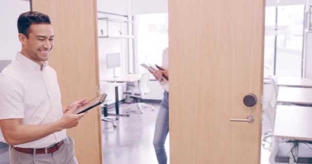 4k video footage of a cheerful young businessman greeting his colleagues as he walks through his office — Vídeo de Stock