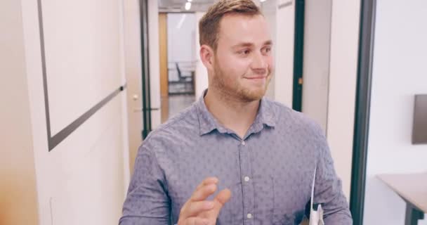 4k video footage of a cheerful young businessman greeting his colleague as he walks through his office — Stok video