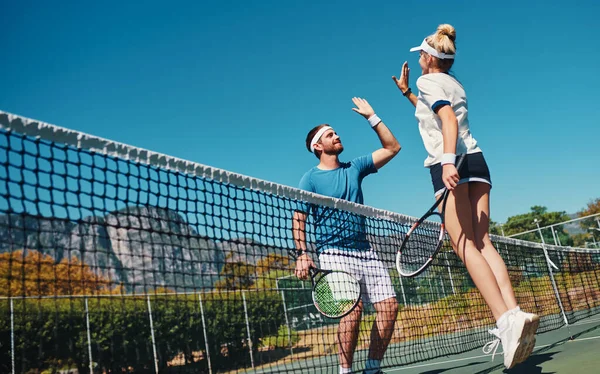 Youre dabei erstaunlich. Aufnahme in voller Länge von zwei jungen Tennisspielern, die sich im Freien auf dem Platz eine hohe Fünf geben. — Stockfoto