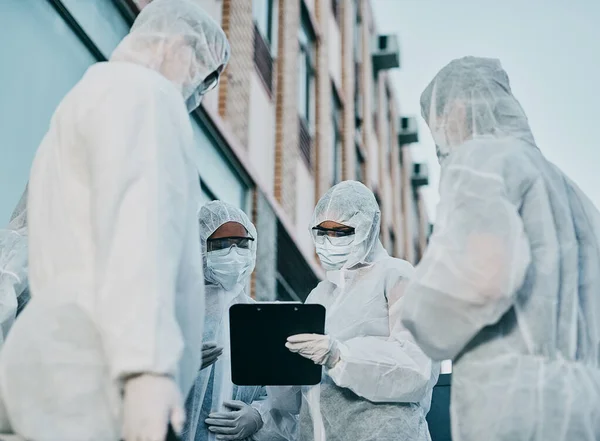 A csapatmunka működteti a fertőzésellenőrzést. Lelőtték egy csoport egészségügyi dolgozóról, akik vegyvédelmi ruhát viseltek, és együtt dolgoztak egy járványkitörés során a városban.. — Stock Fotó