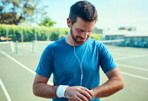 Sou bom com o tempo. Tiro de um jovem desportivo verificando seu relógio enquanto se exercita em um campo de ténis. — Fotografia de Stock