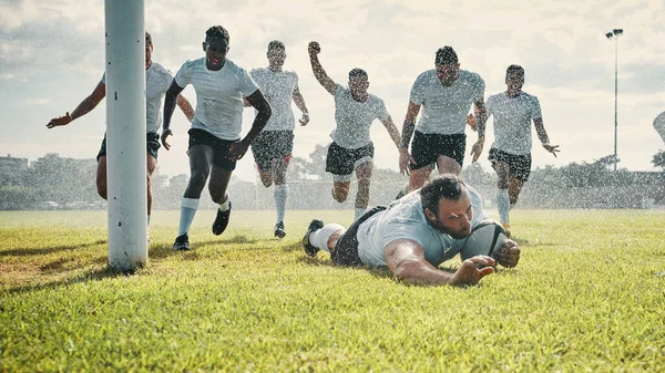 La lluvia no lo detiene. Tiro de longitud completa de un joven jugador de rugby guapo anotando una oportunidad mientras entrena en un día lluvioso. —  Fotos de Stock